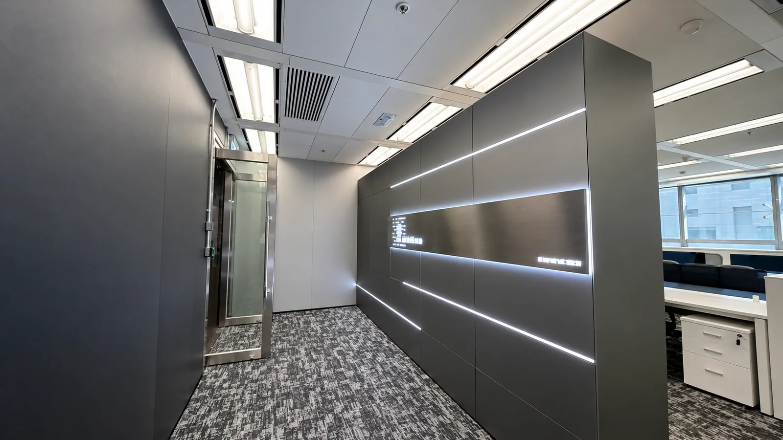 AI-enhanced film still of illuminated wall panels at the office entrance, with a glass door and workstations beyond.