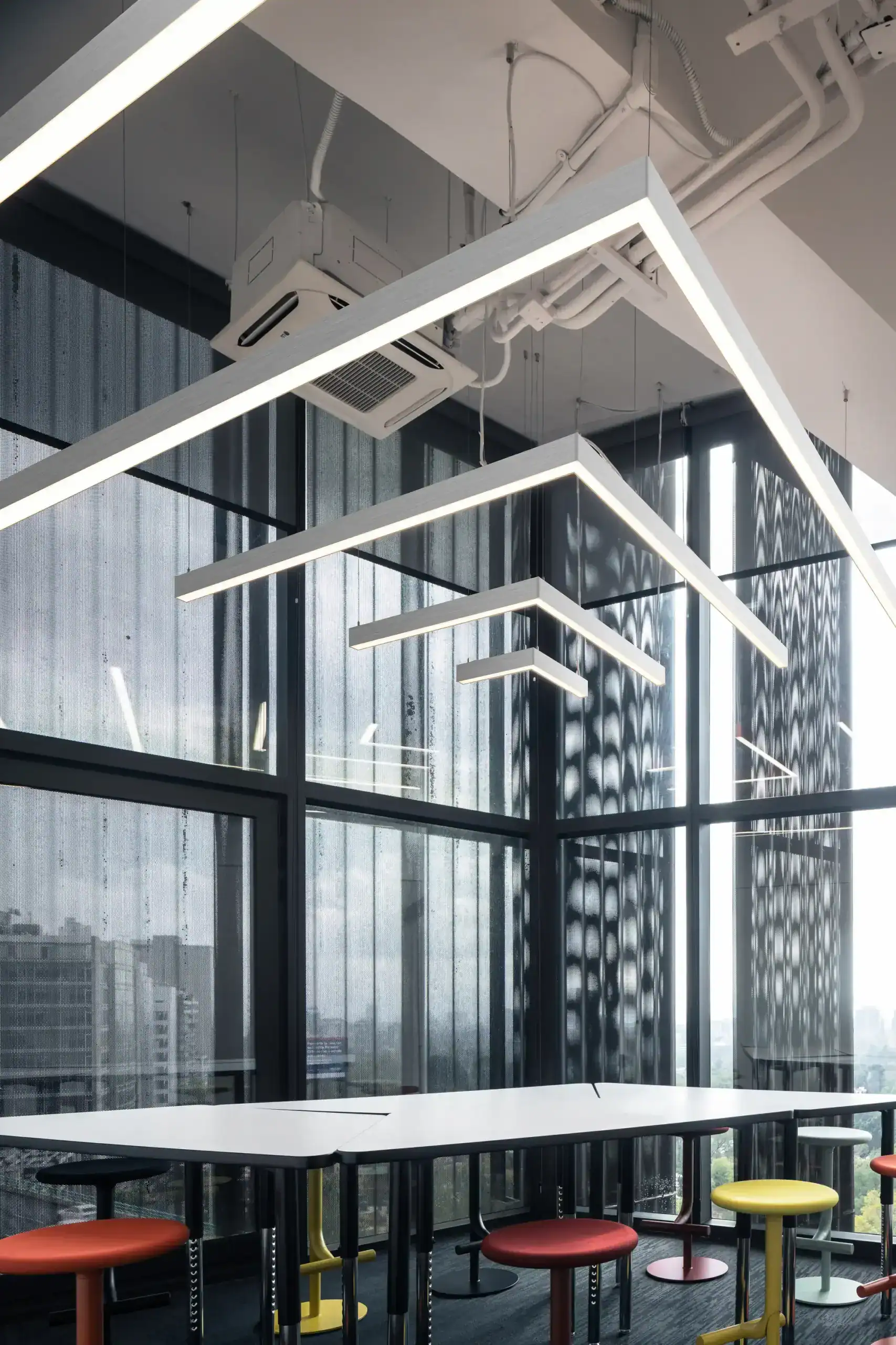 Contemporary high-rise office meeting room with geometric lighting and colorful stools by Roky Design in Hong Kong.